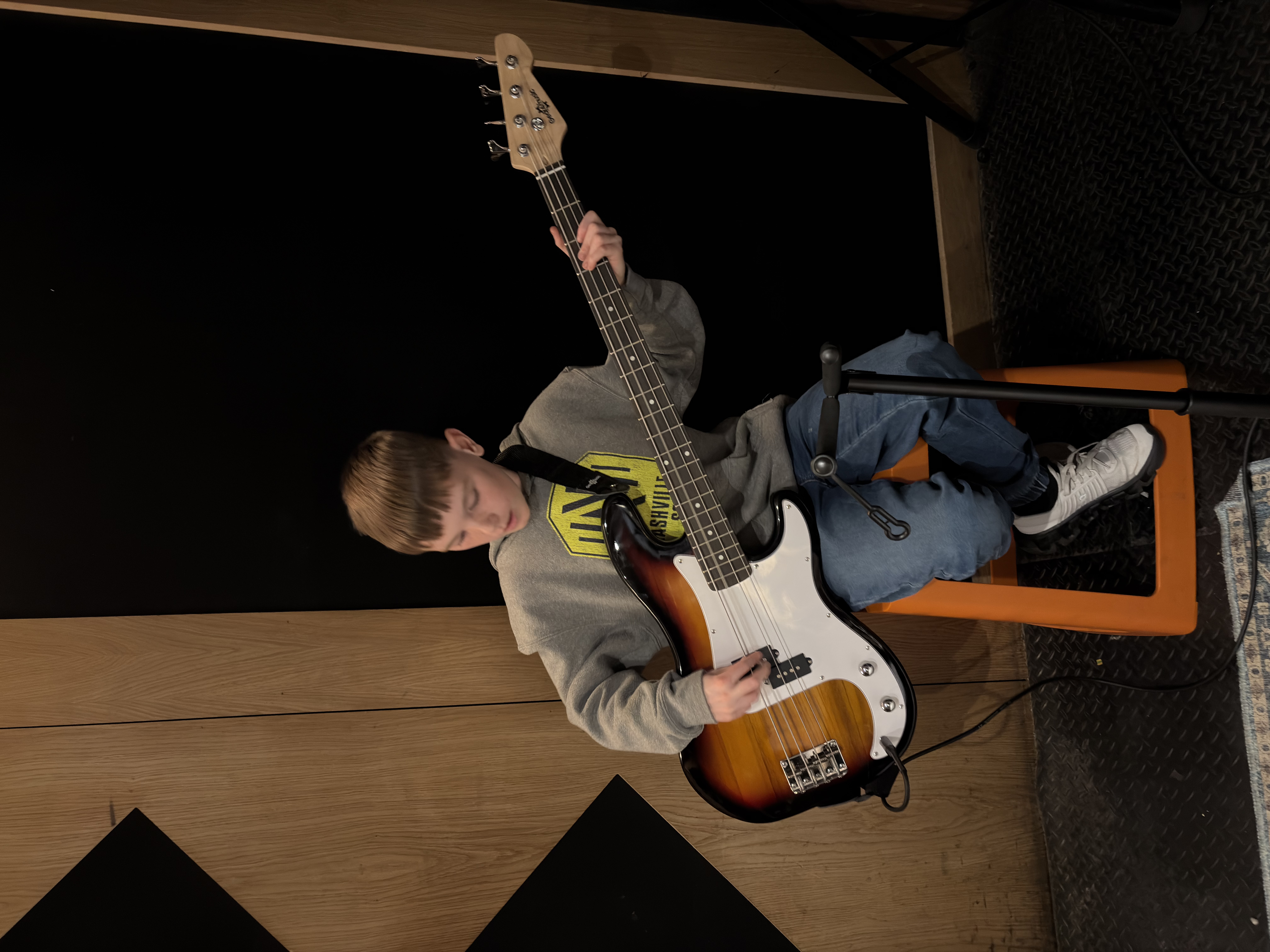 Child seated with a bass guitar during a Band Night rehearsal.