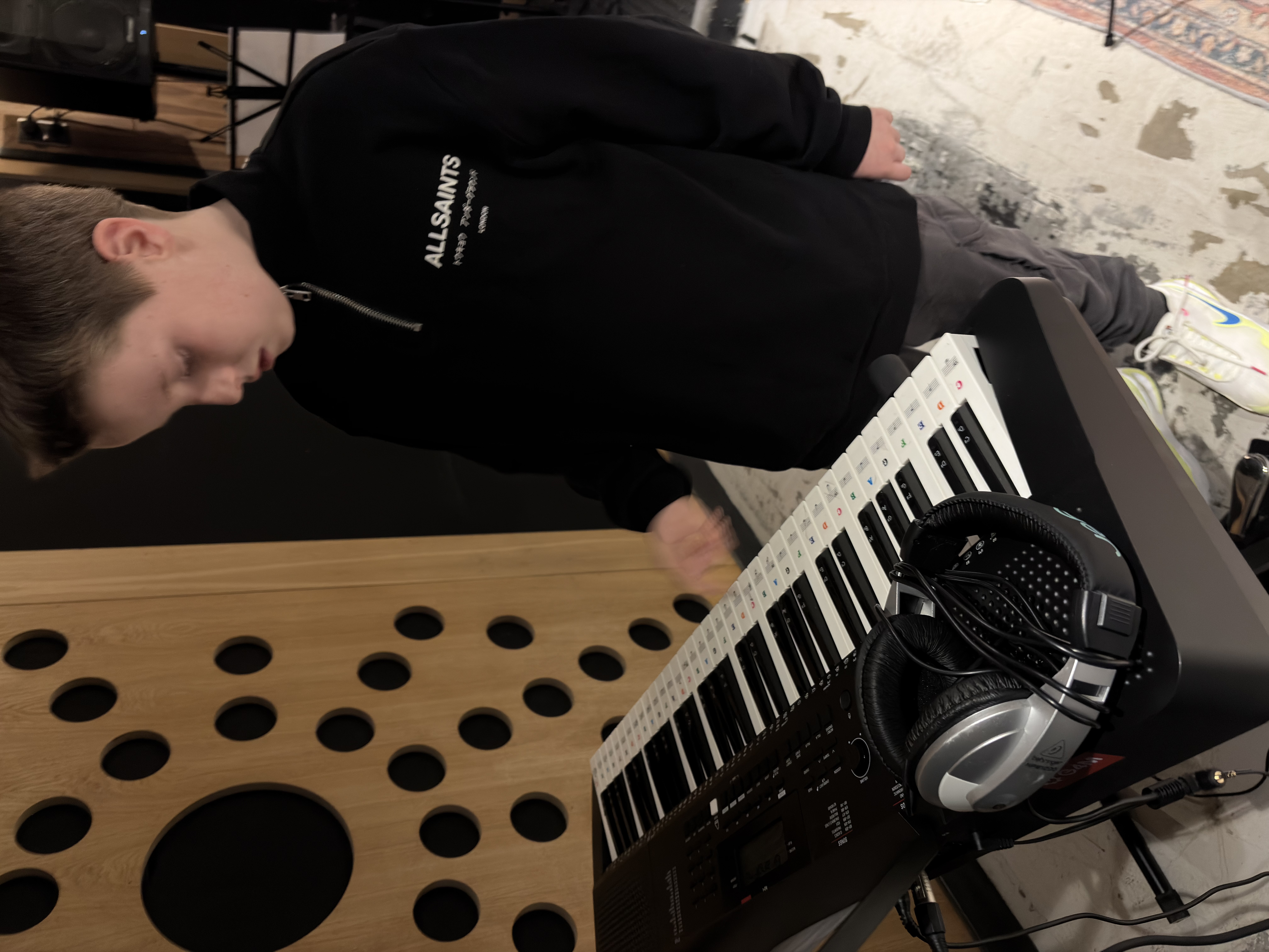 Child playing keyboard with headphones on during a Band Night session.